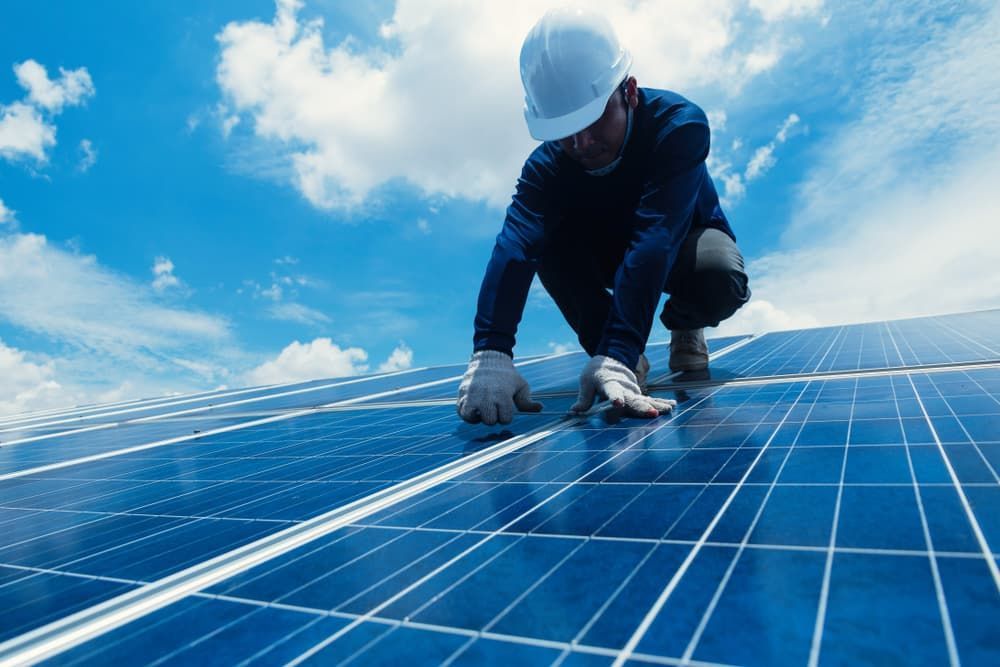 A Man is Working on a Solar Panel on Top of a Roof — SEP Electrical Pty Ltd in Wollongong, NSW