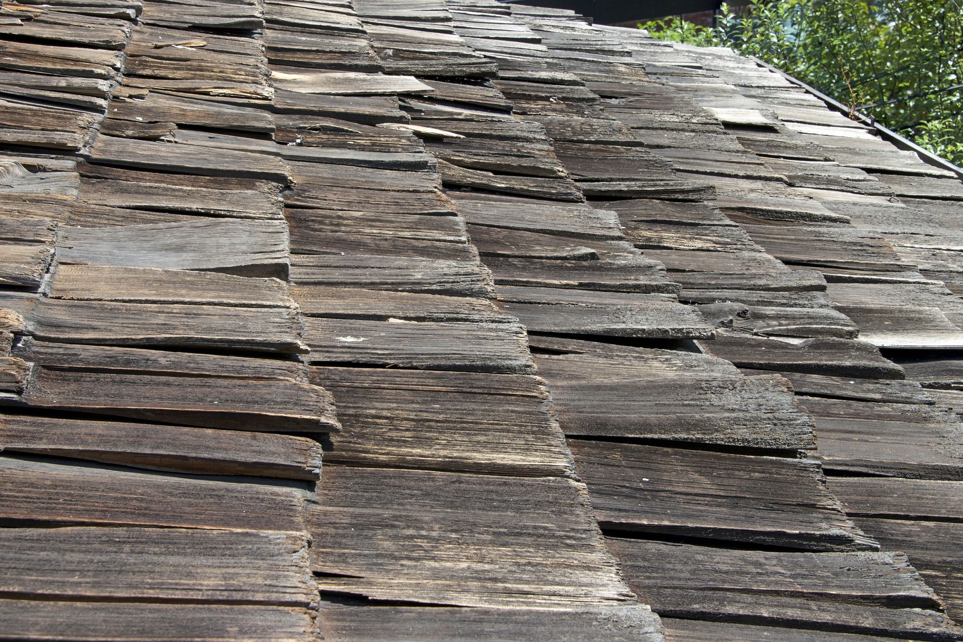 A close up of a roof made of rotting wooden shingles