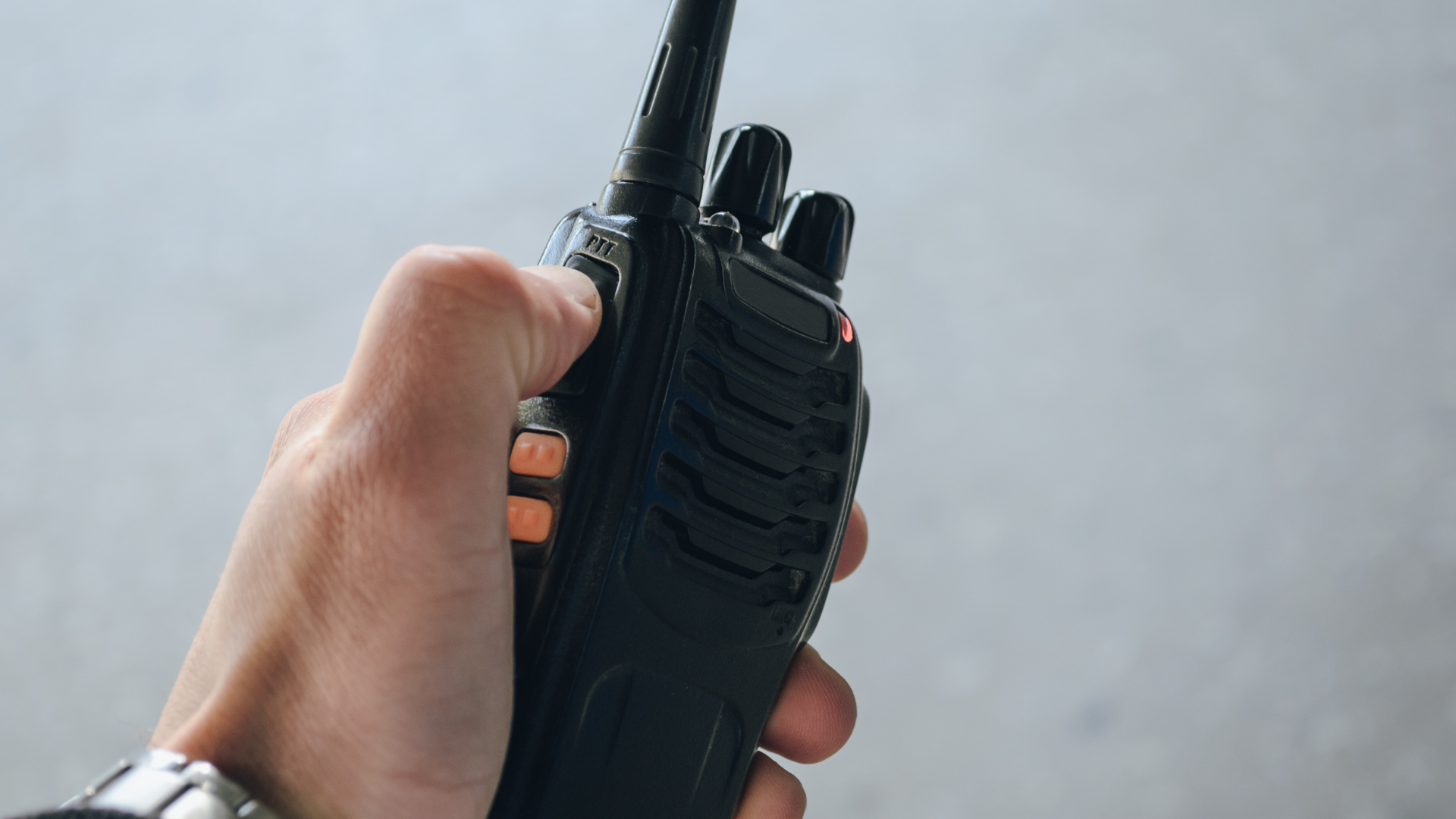A person is holding a walkie talkie in their hand.