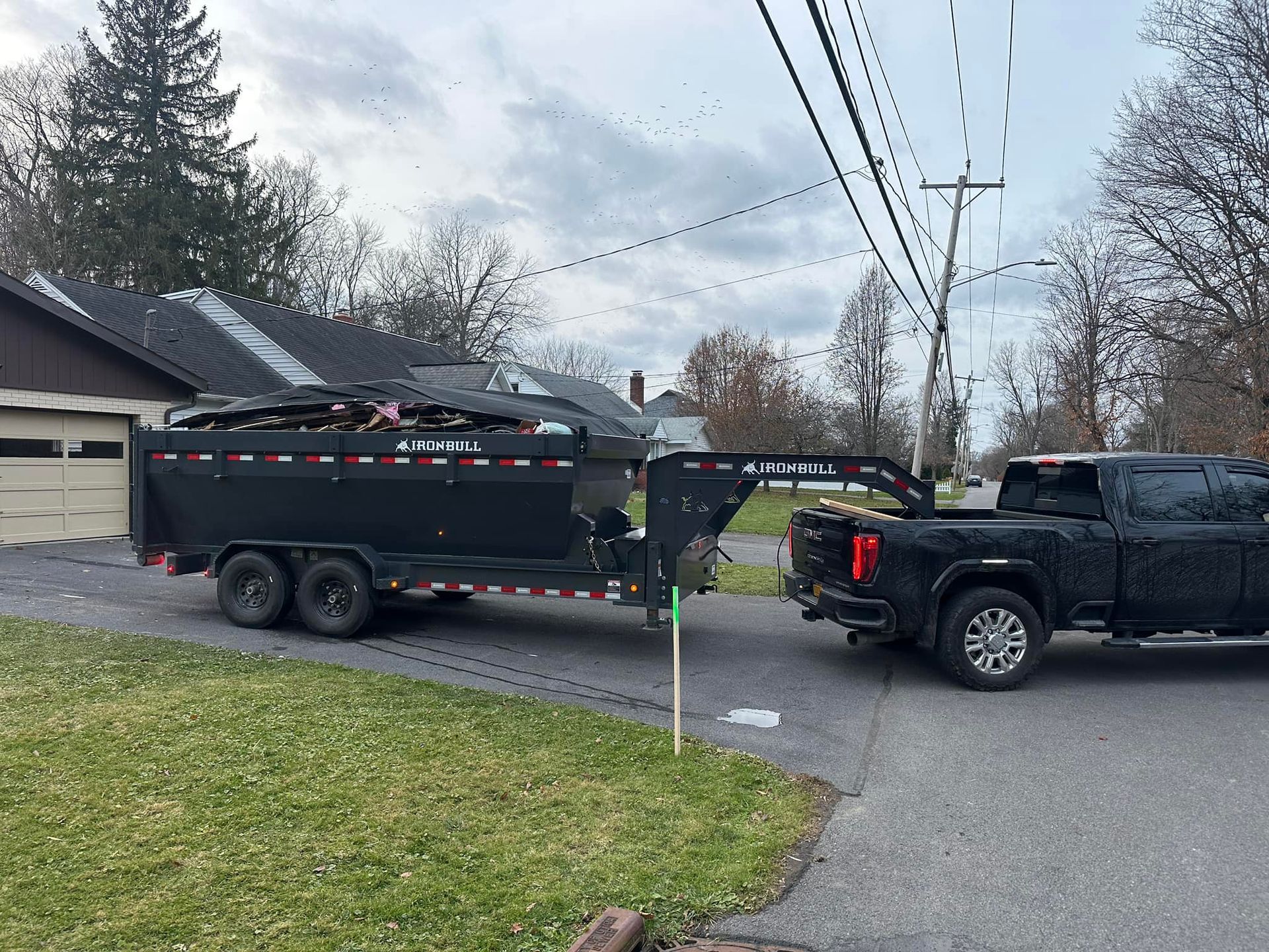A black truck is towing a black trailer down a street.