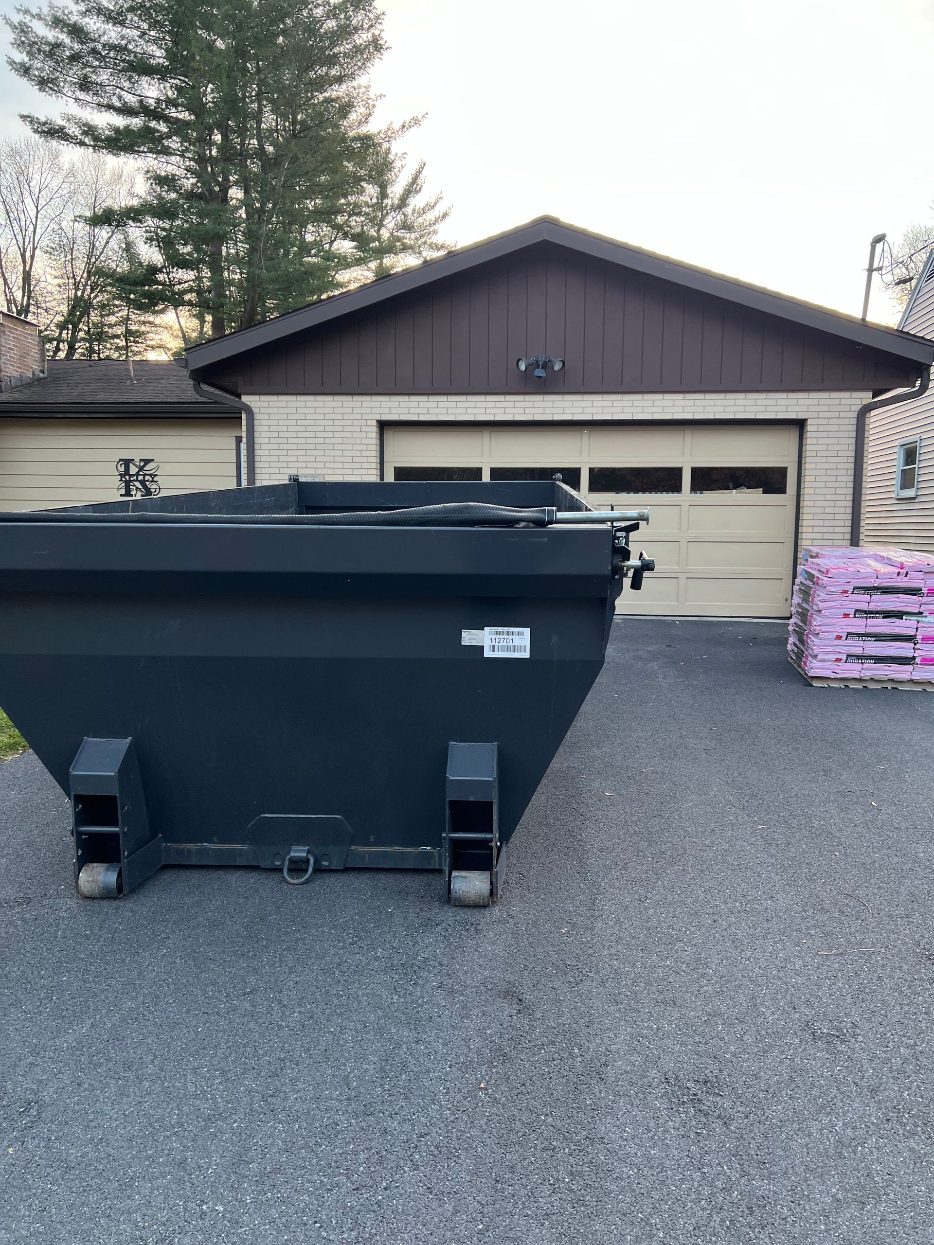A dumpster is parked in front of a garage.