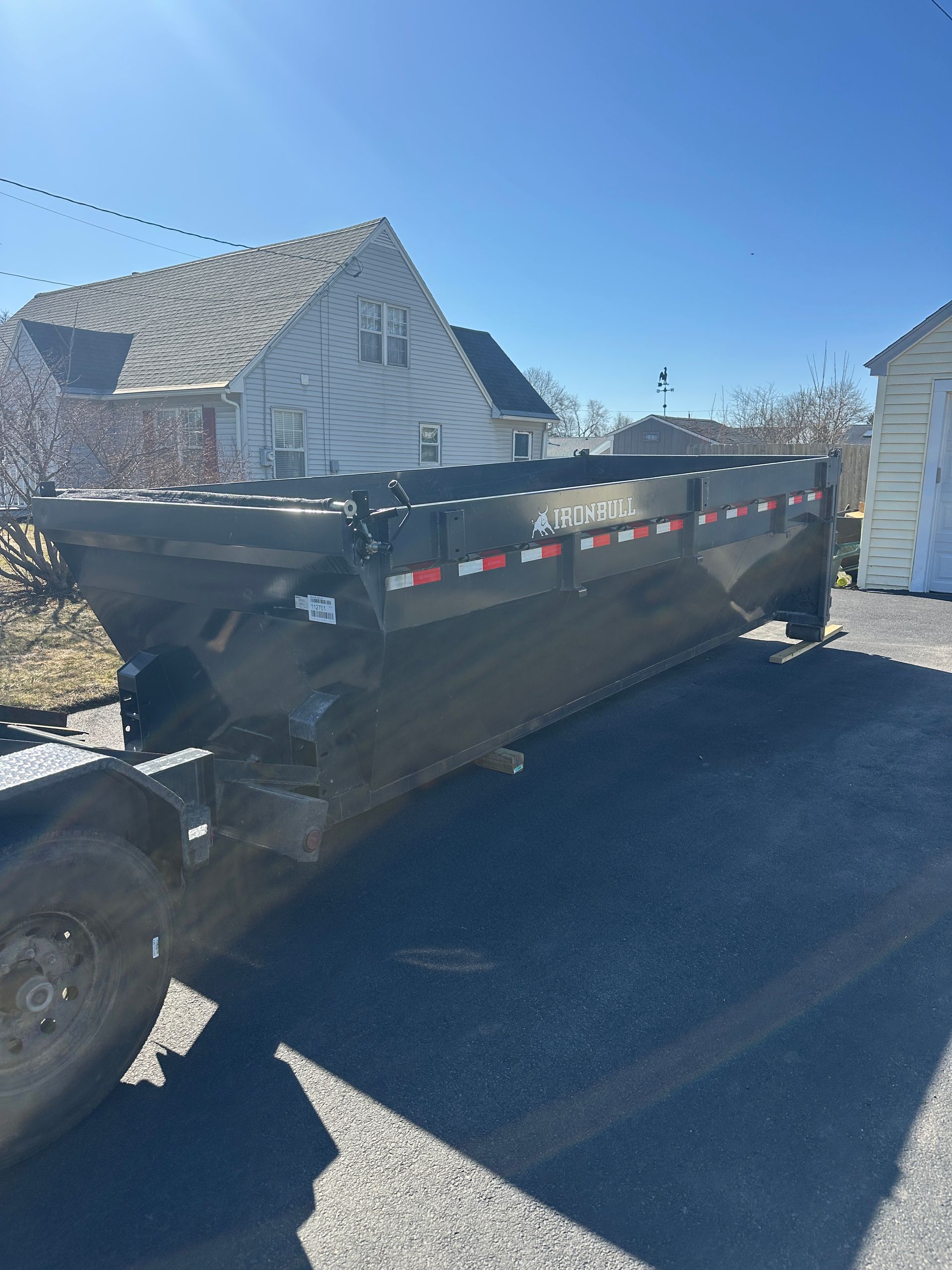 A dumpster is parked on the side of the road in front of a house.