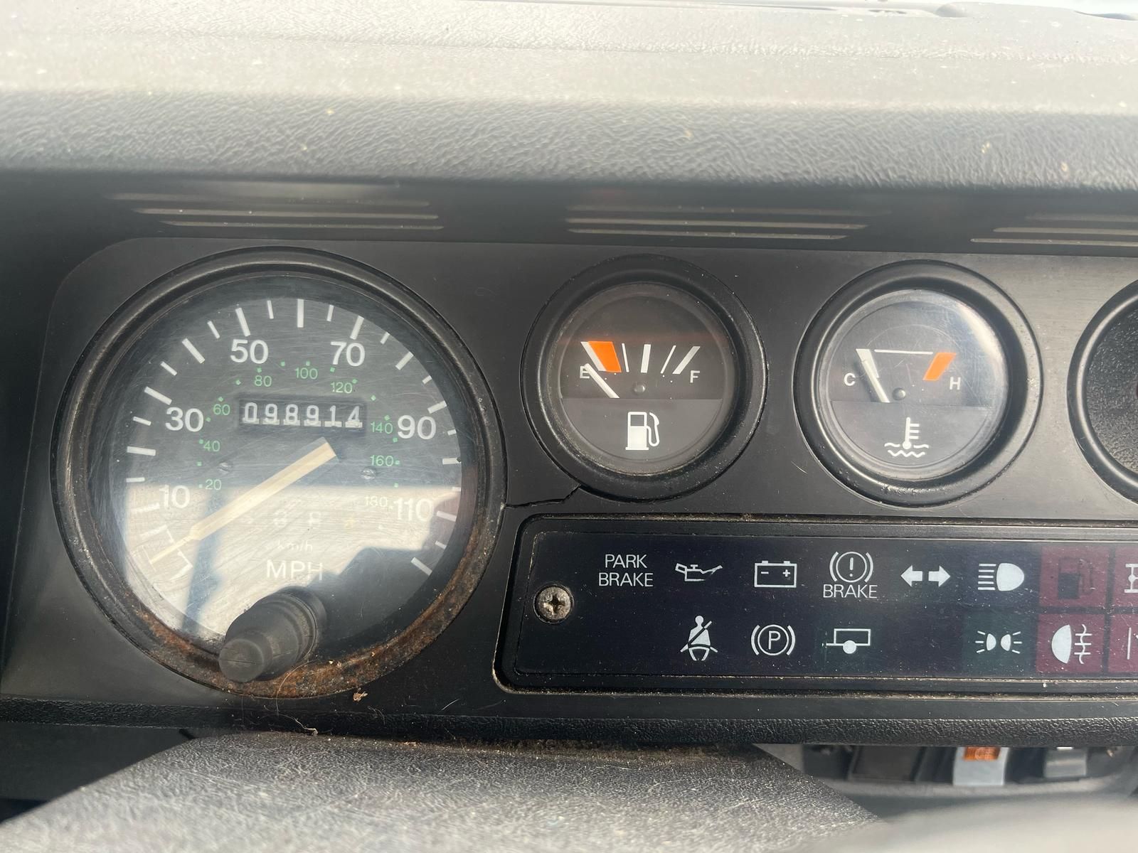 Dashboard of a vehicle showing a speedometer, fuel gauge nearly empty, and temperature gauge. The odometer reads 028884.