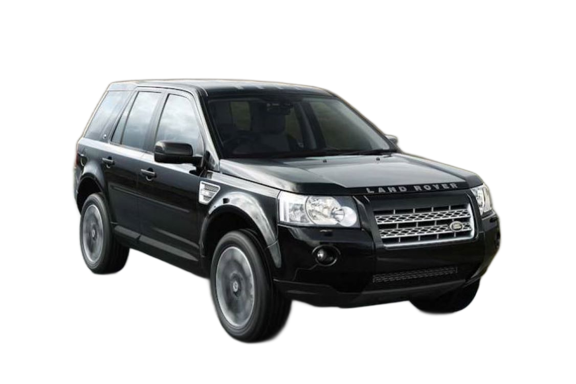 Black Land Rover Freelander SUV driving on a wet road with a blurred background of hills and a bridge.