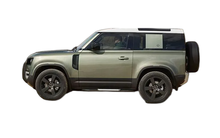 A green Land Rover Defender with a white roof is driving on a dirt road with a person standing on top of the vehicle.