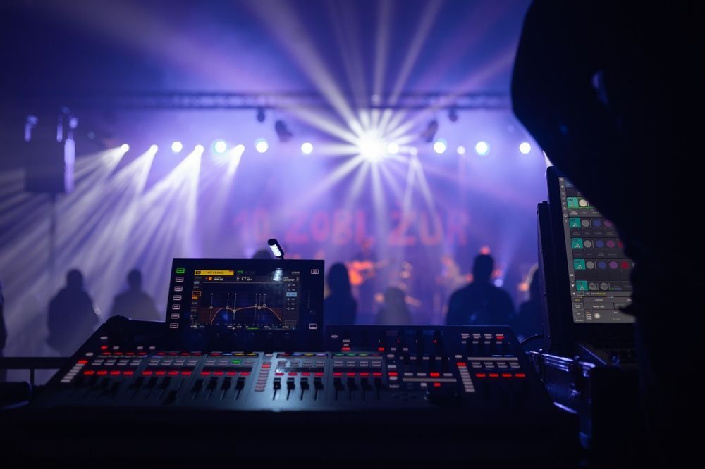 A person is standing in front of a mixer in a dark room.