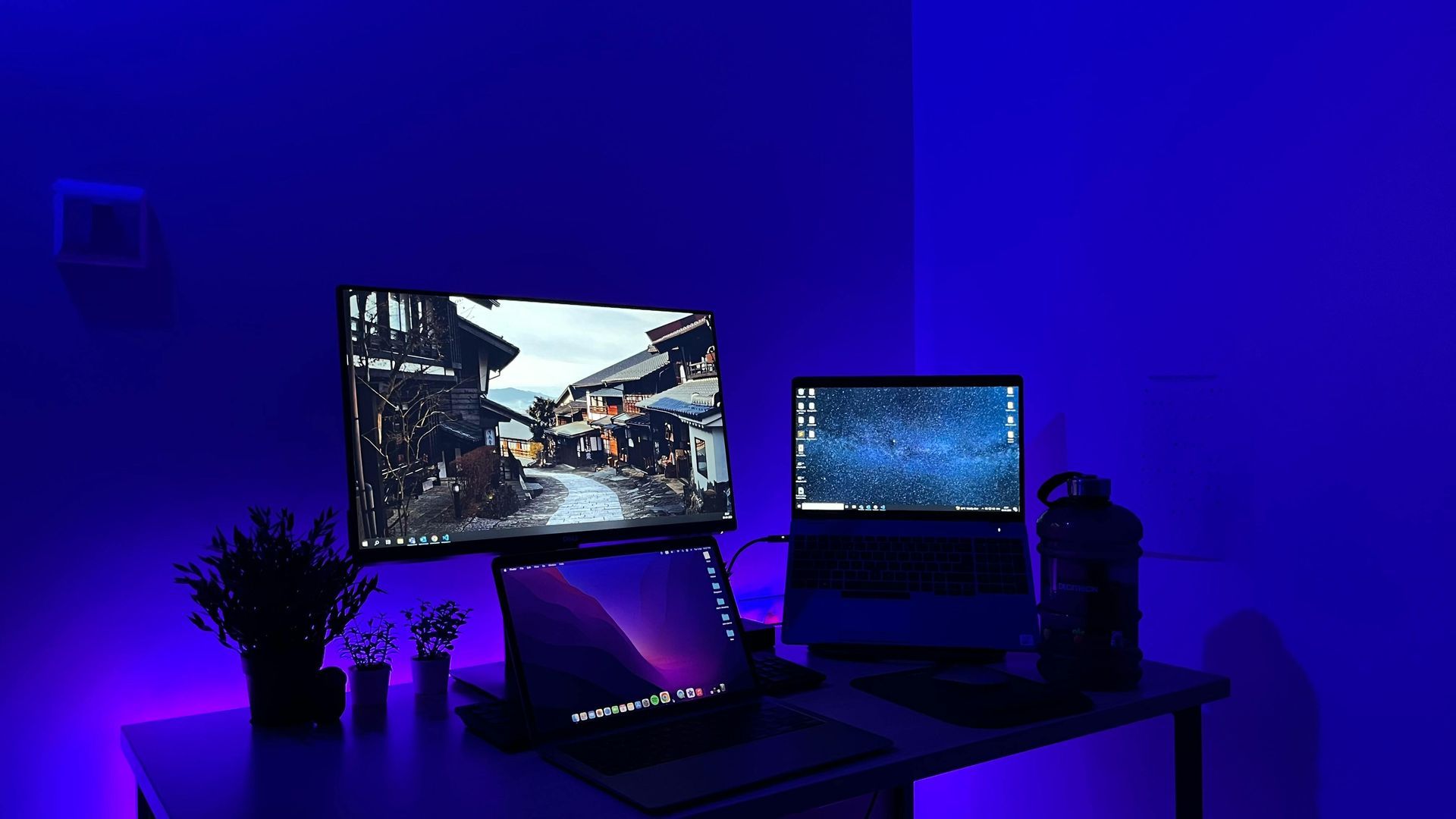 Desk setup with dual monitors, blue lighting, and a water bottle.
