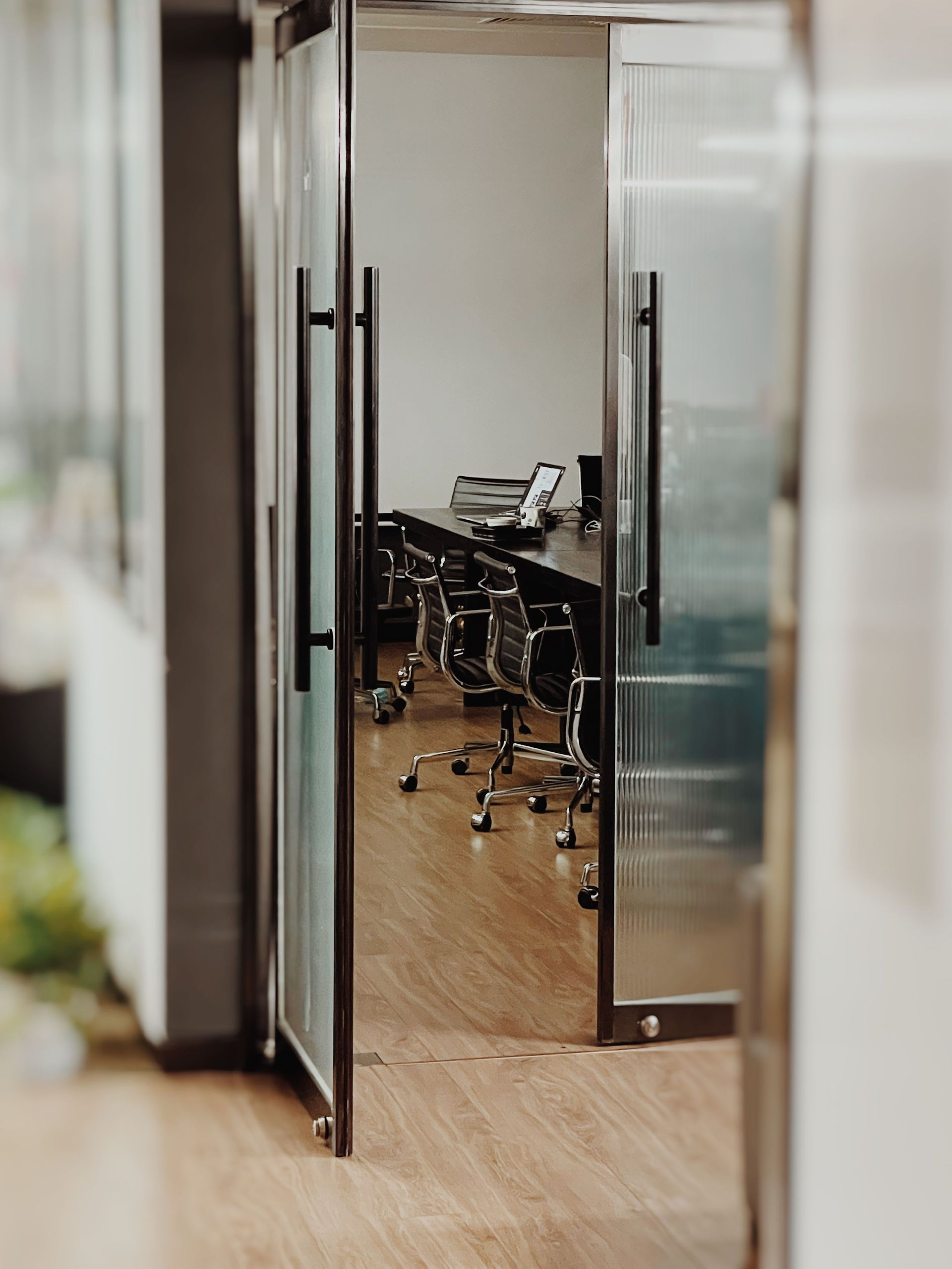 Empty office conference room with glass doors and chairs around a wooden table