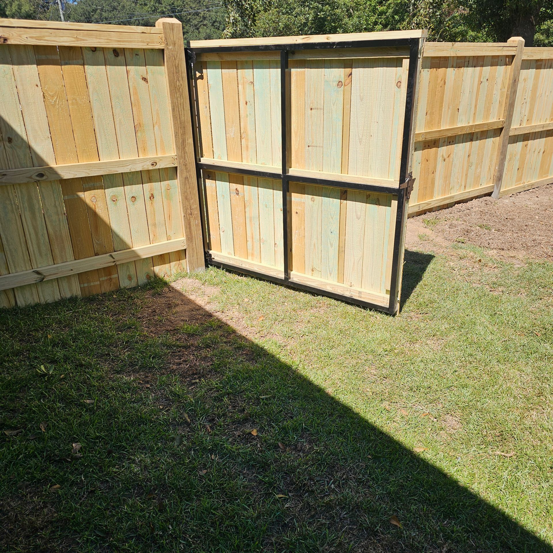 A wooden fence with a gate in the backyard.