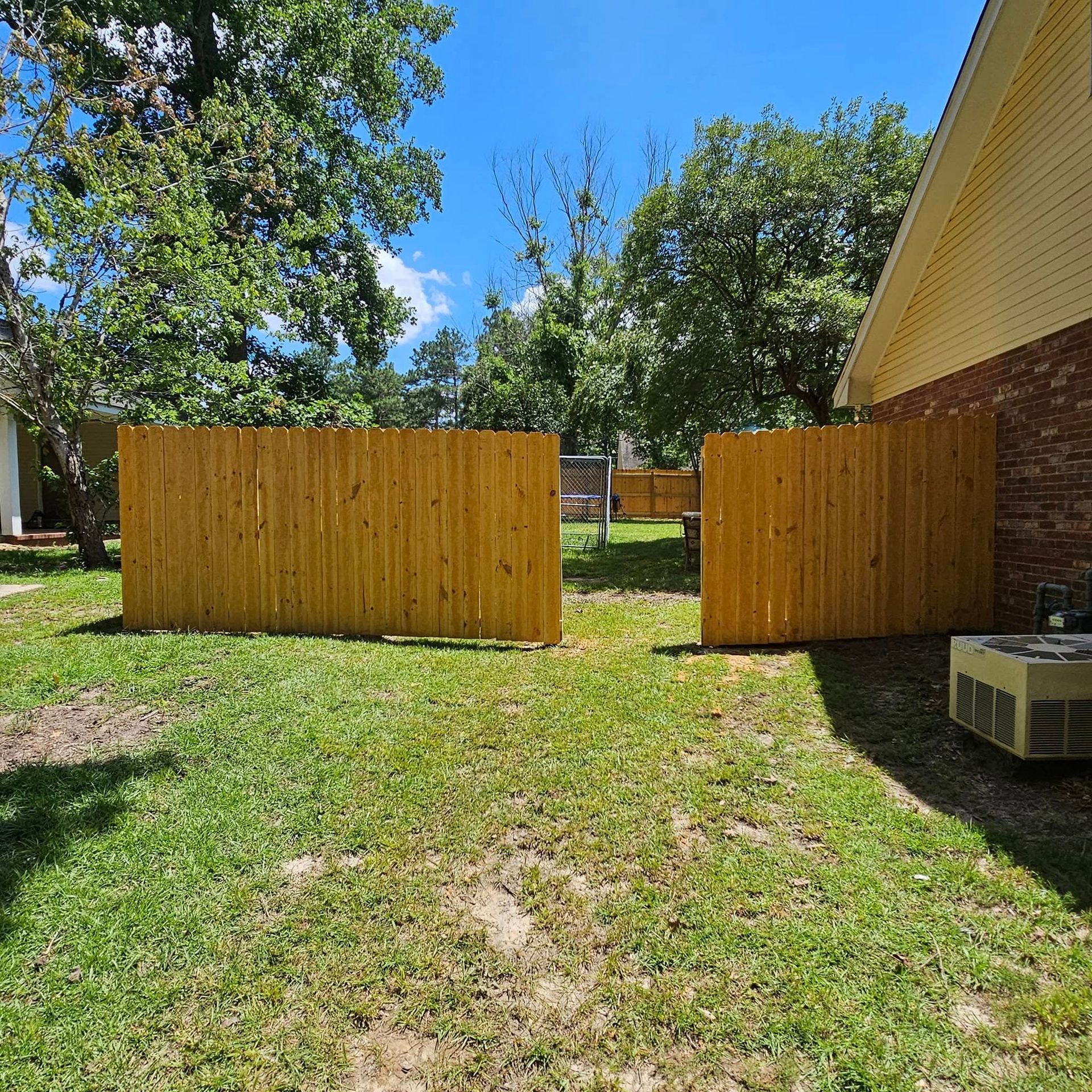 A wooden fence is in the backyard of a house.