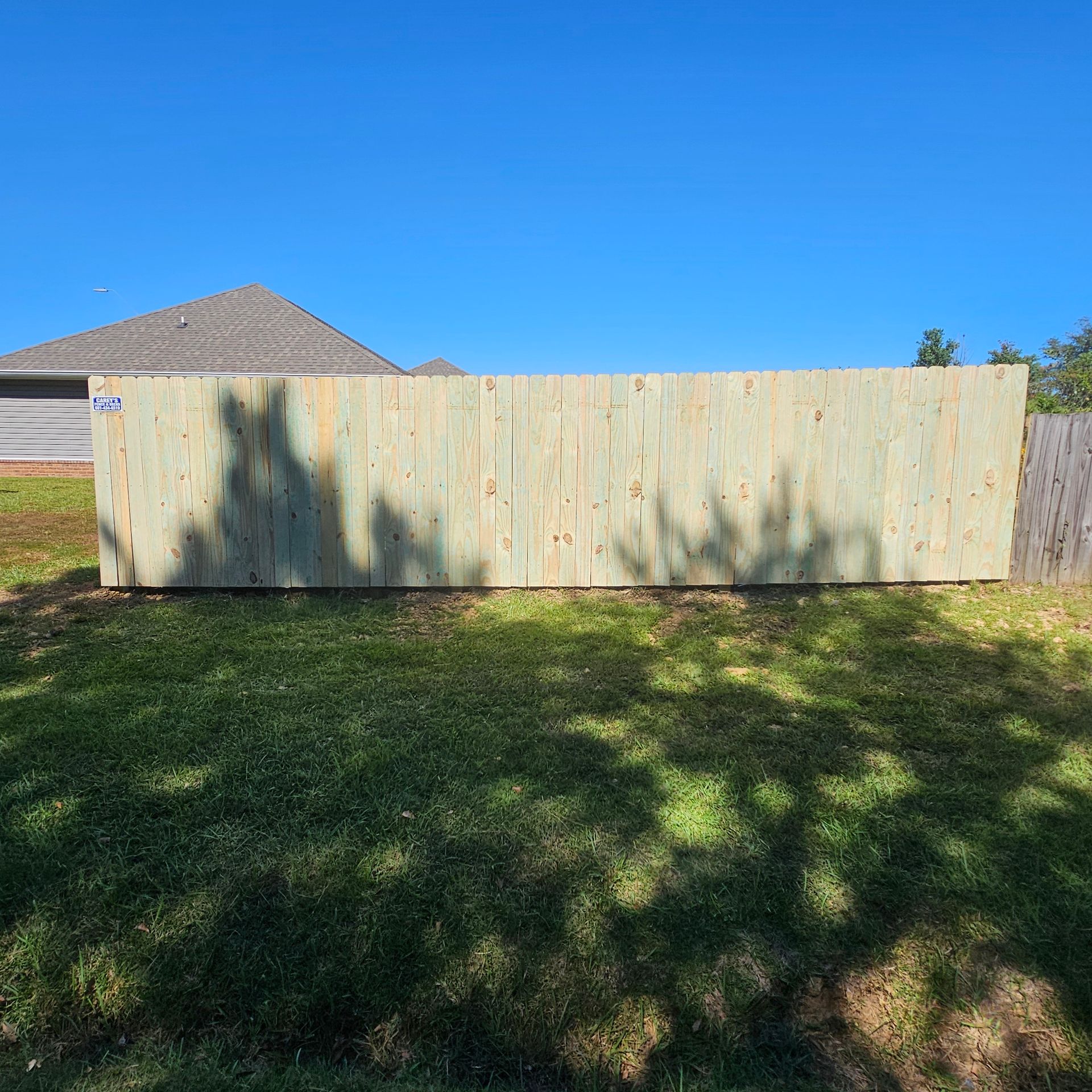 A wooden fence is sitting in the middle of a lush green field.