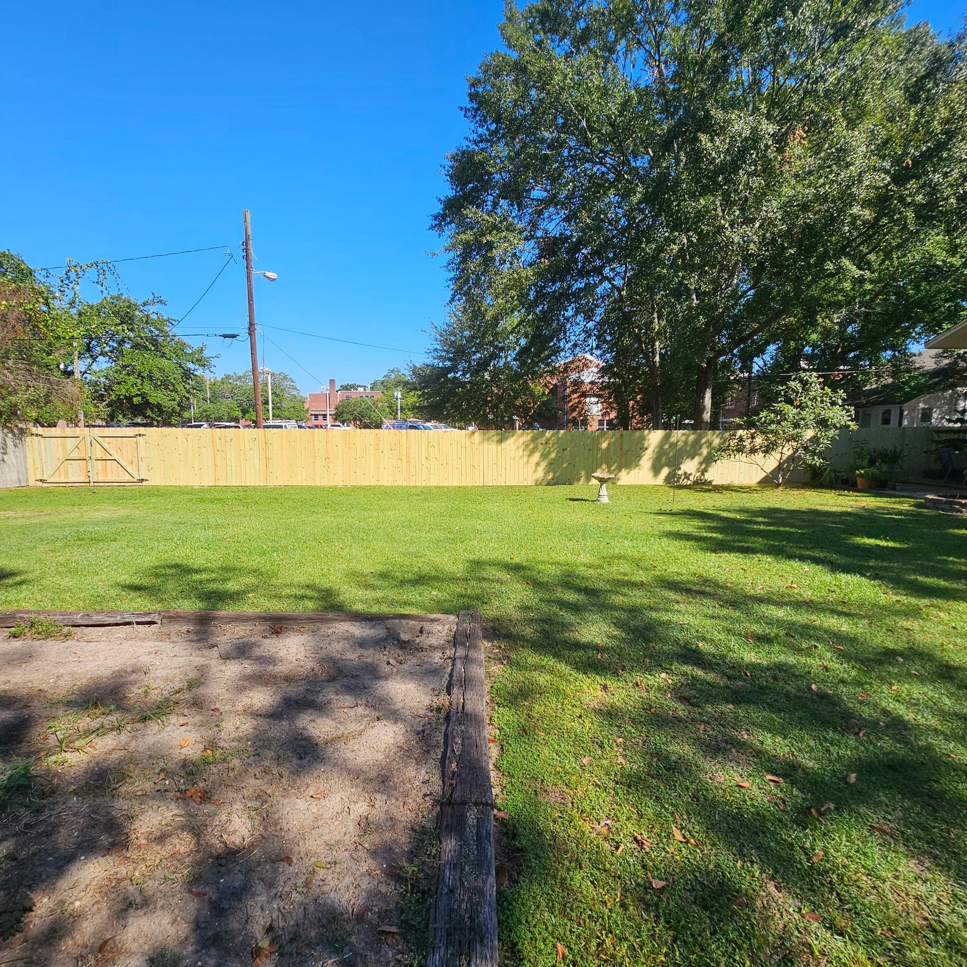 A yard with a wooden fence and trees in the background