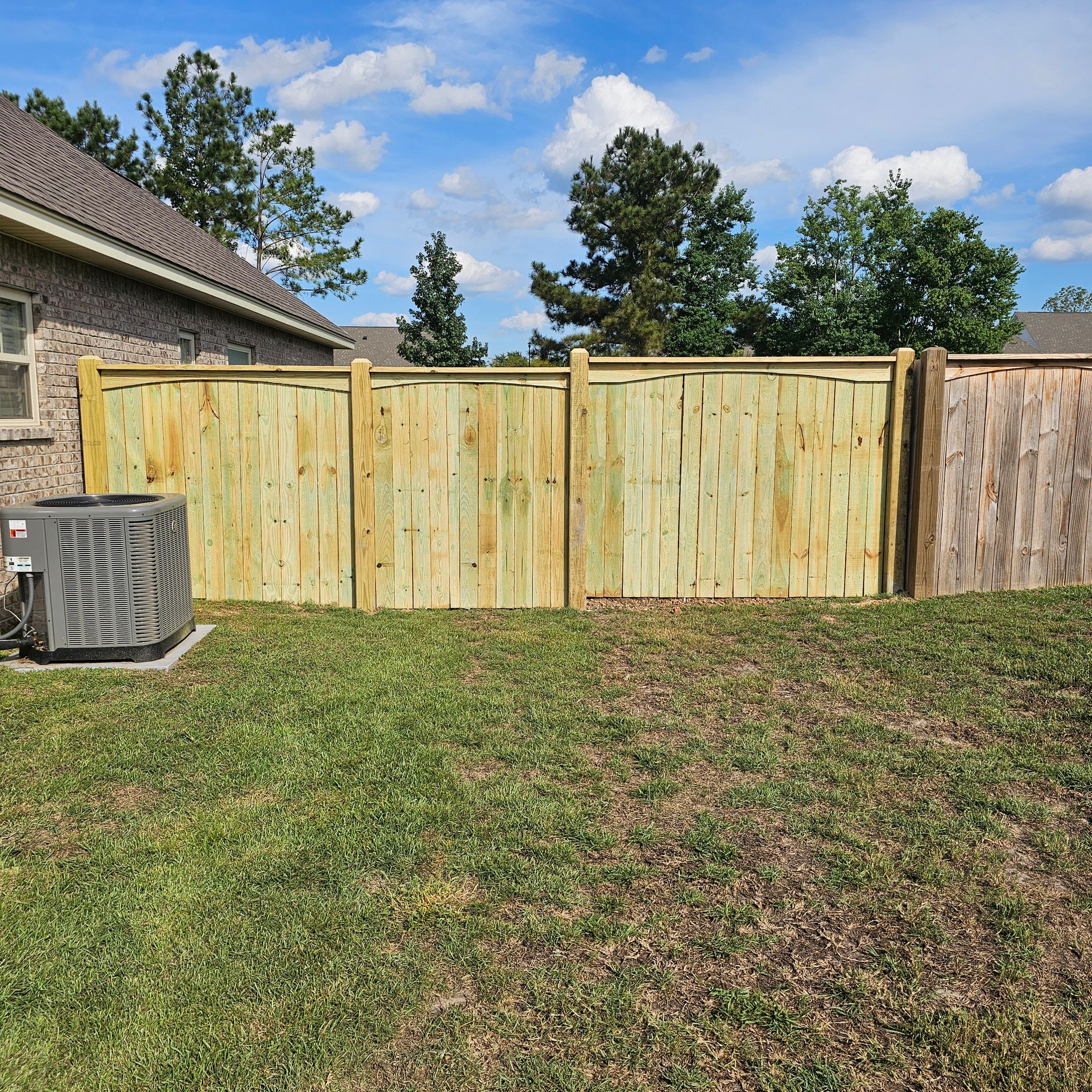 A wooden fence is in the backyard of a house.