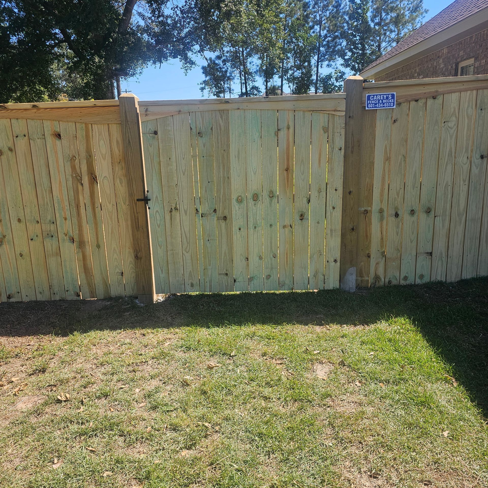 A wooden fence with a gate in the backyard of a house.