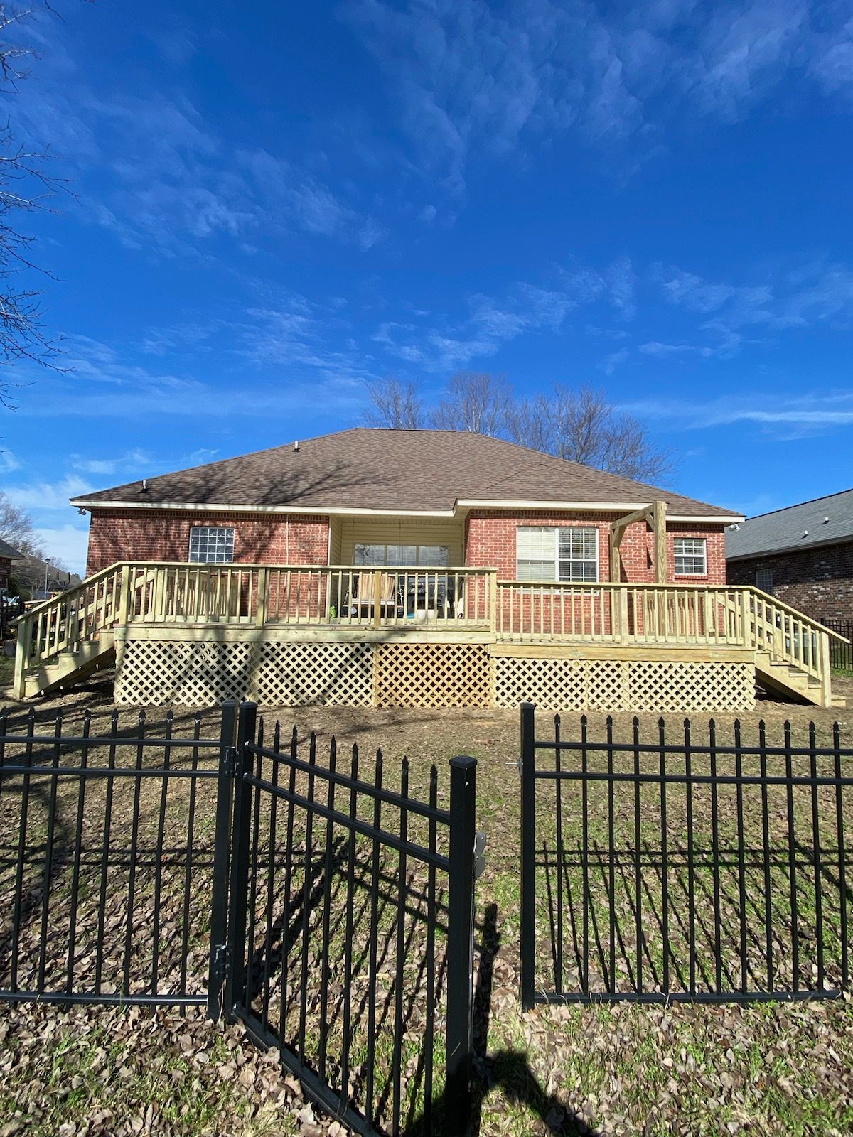 A house with a large deck and a fence in front of it.