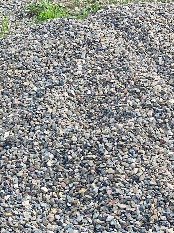 A pile of gravel is sitting on the ground in a field.