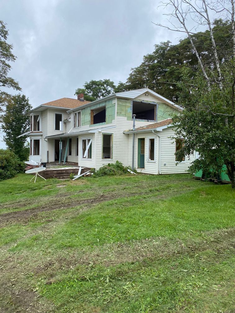 A large white house is sitting on top of a lush green field.