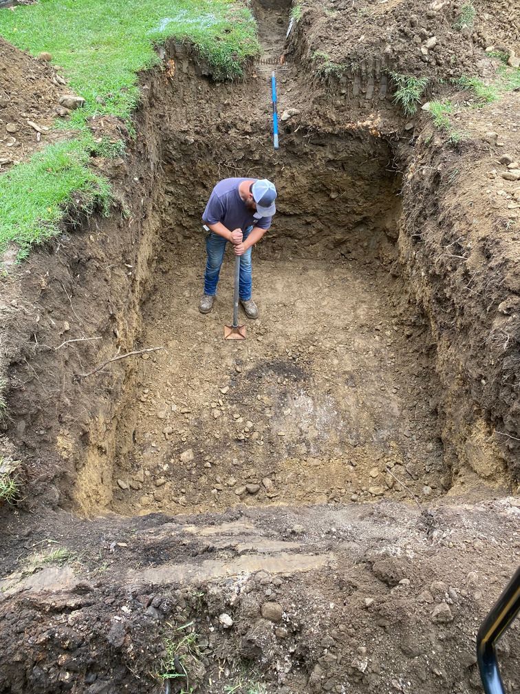 A man is digging a hole in the dirt with a shovel.
