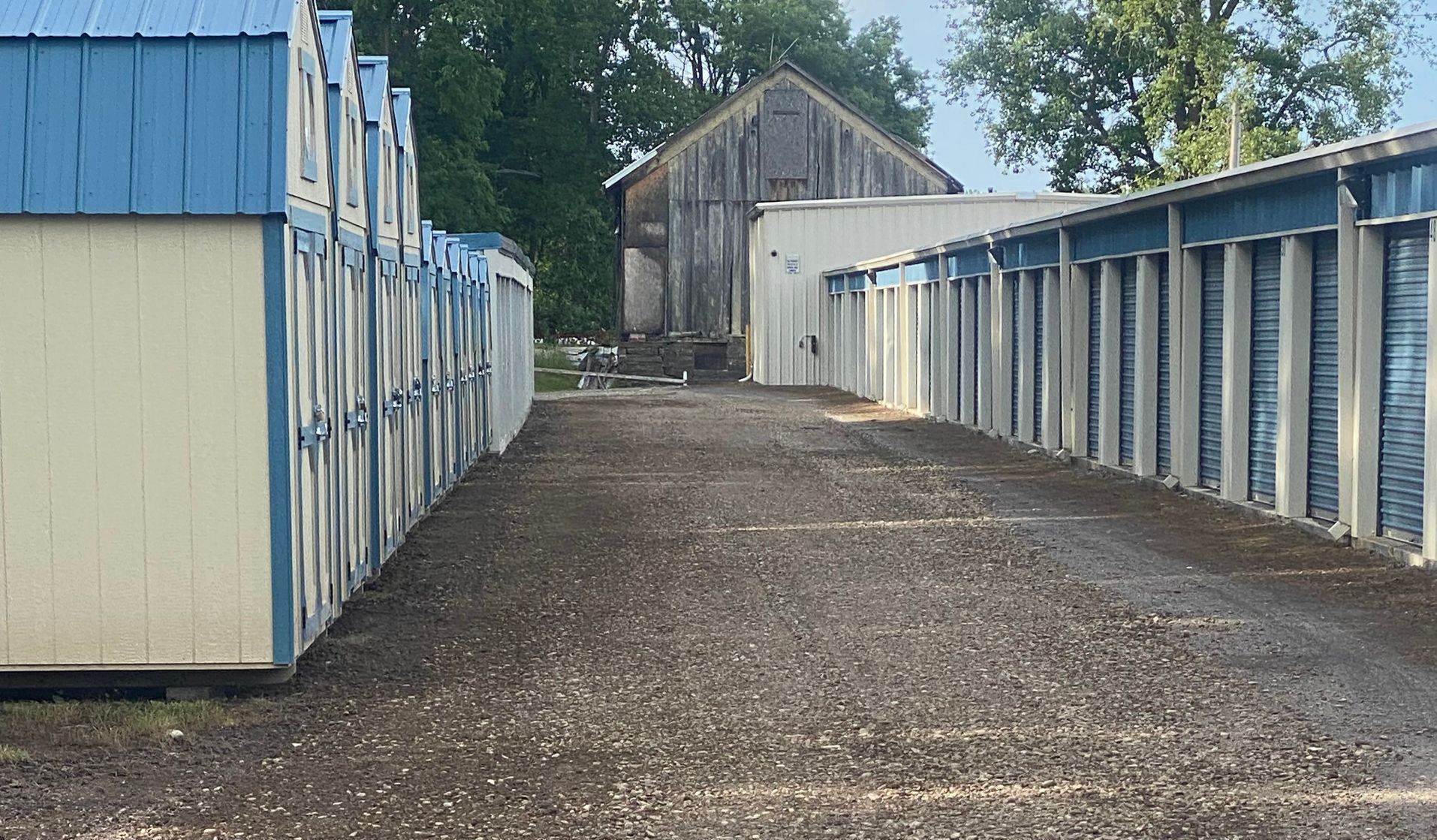 A row of storage units lined up next to each other on a gravel road.