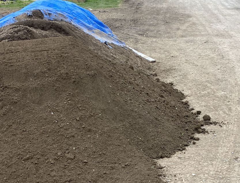 A pile of dirt is sitting on the side of a dirt road.