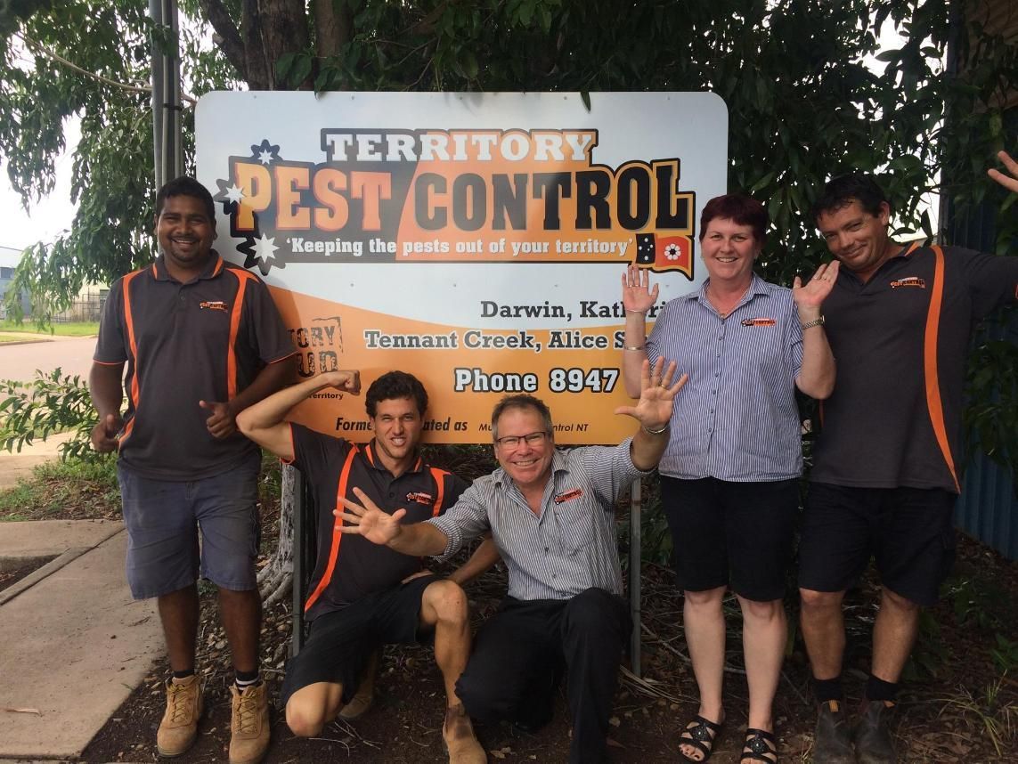 A Group of People Posing in Front of a Territory Pest Control Sign — Territory Pest Control In Winnellie, NT