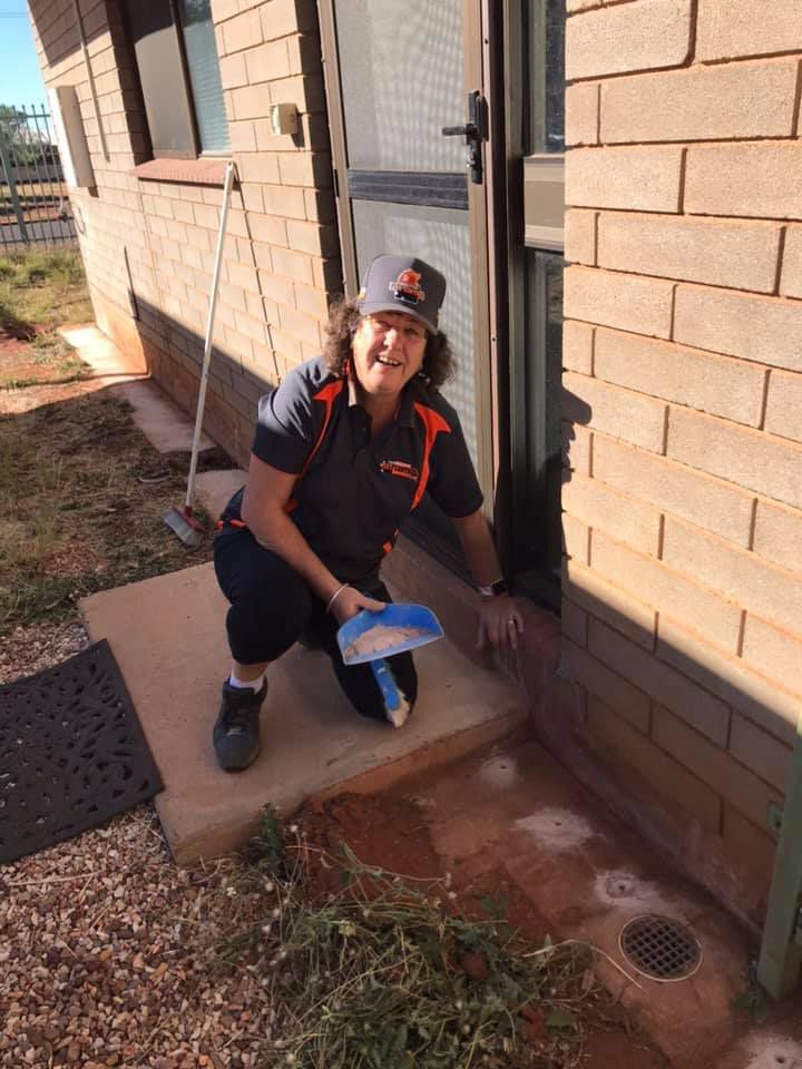 A Woman Treating Pests in Front of a House — Territory Pest Control In Winnellie, NT