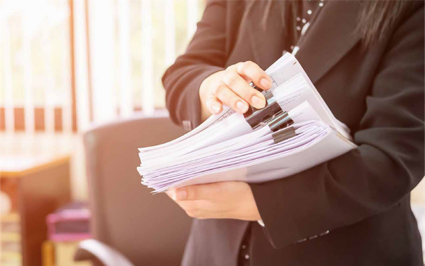 A woman in a suit is holding a stack of papers in her hands.