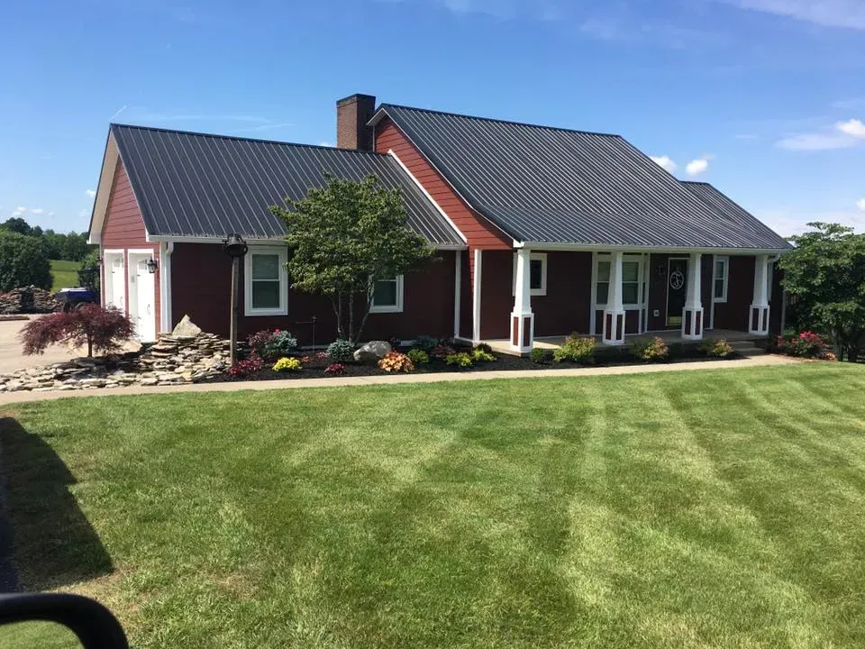 A red house with a black roof is sitting on top of a lush green lawn.
