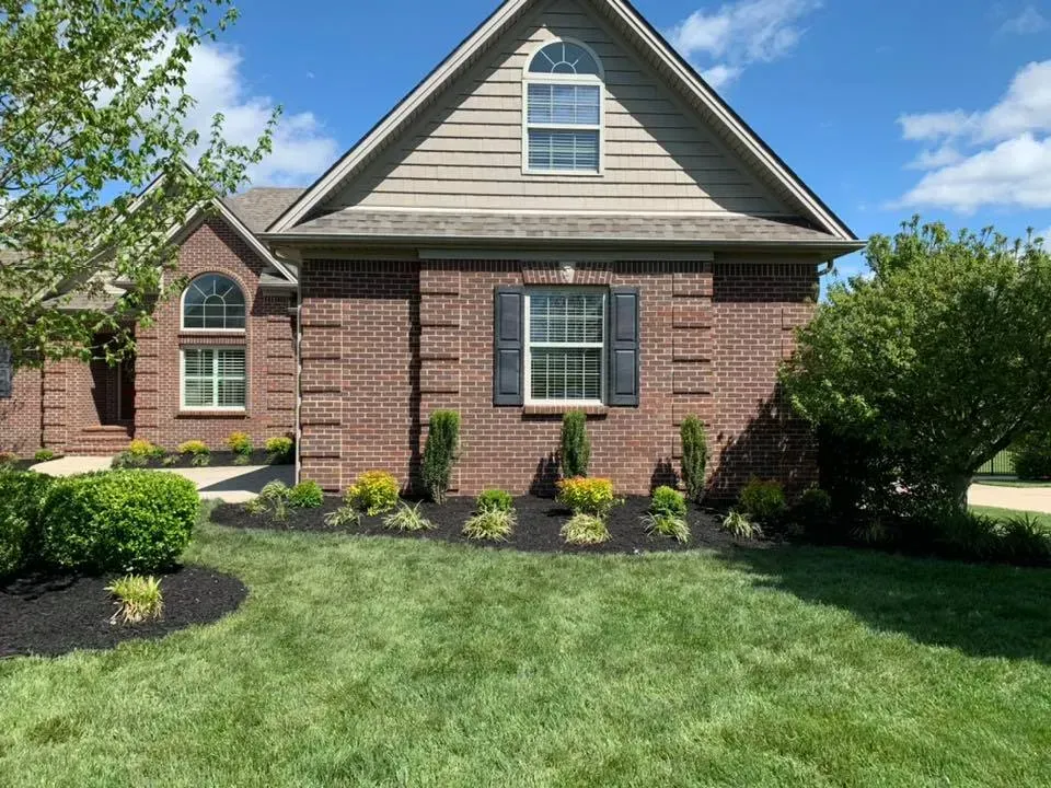 A brick house with a lush green lawn in front of it.