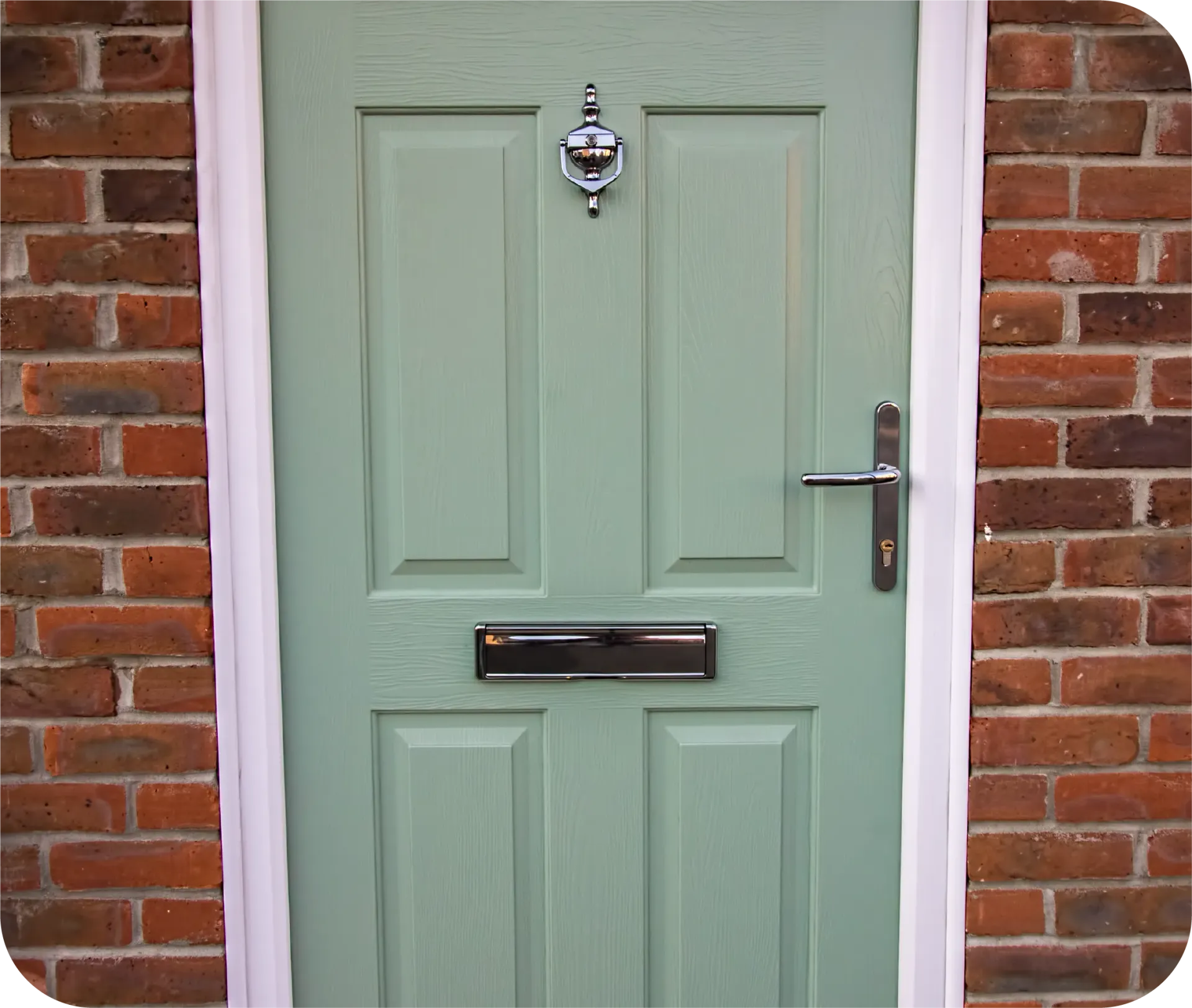 A light green front door with a chrome knocker and letterbox, set within a red brick wall.