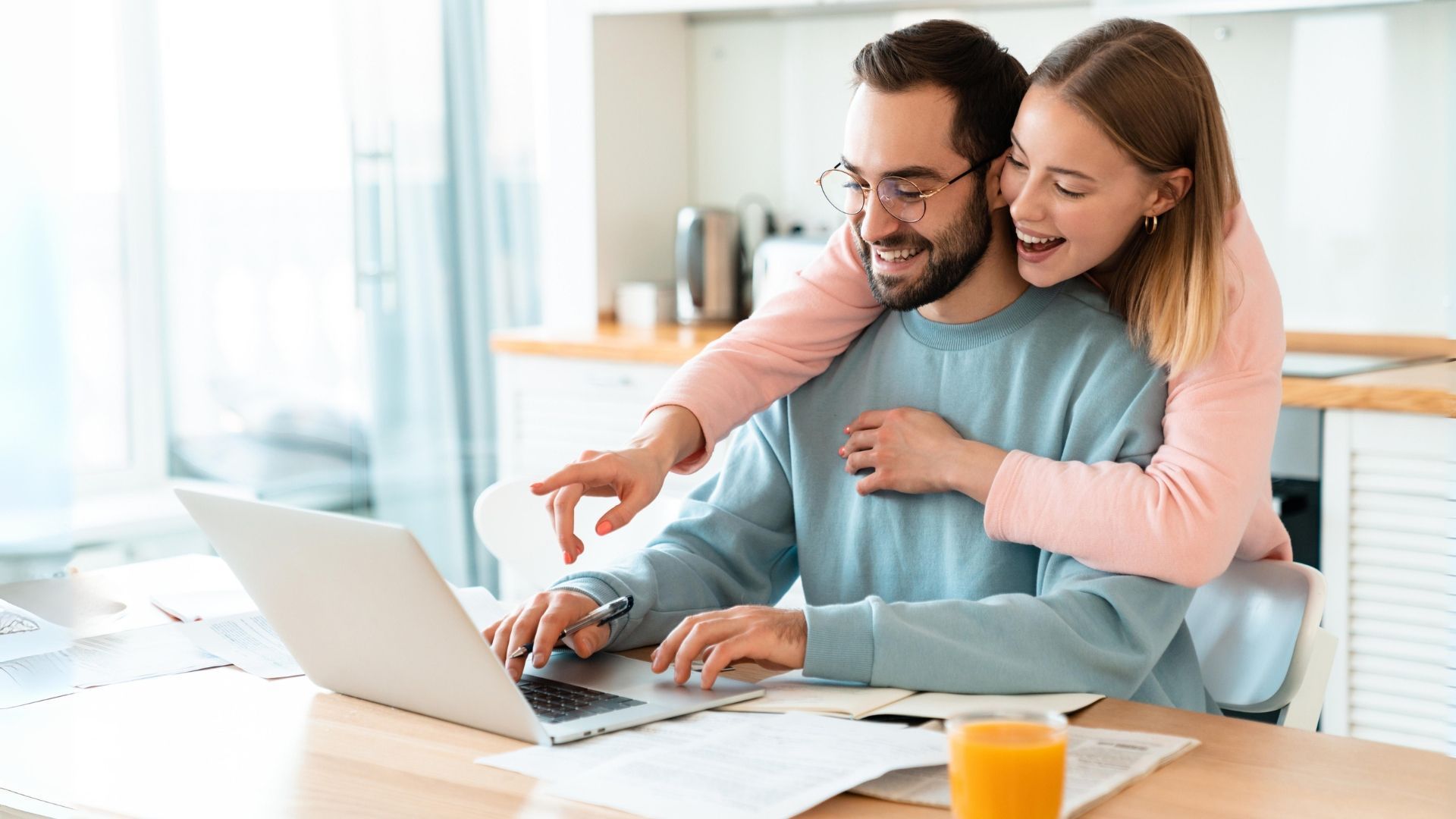 A happy couple looking at an email marketing campaign in their kitchen over breakfast