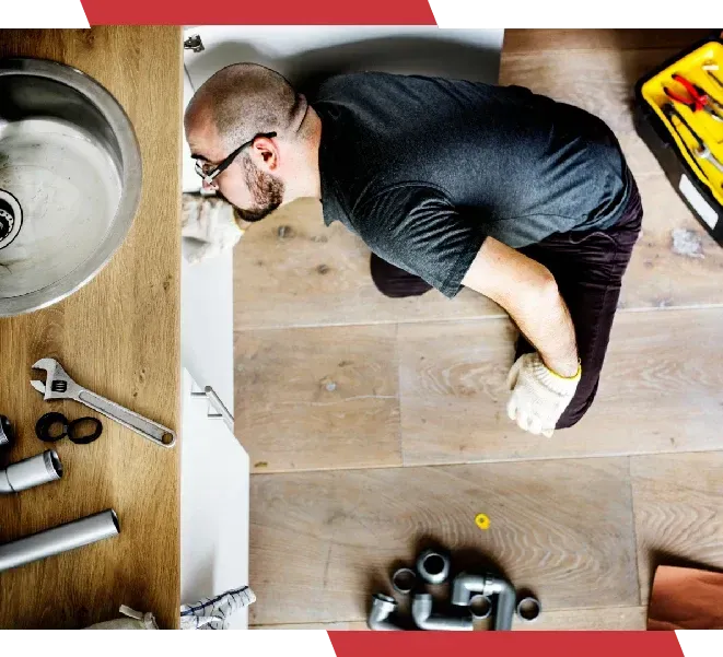 A man is fixing a sink in a kitchen.