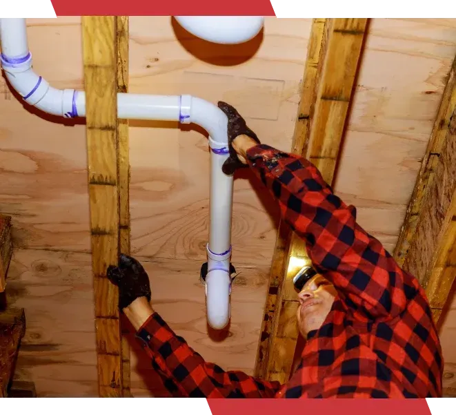 A man in a plaid shirt is working on a pipe
