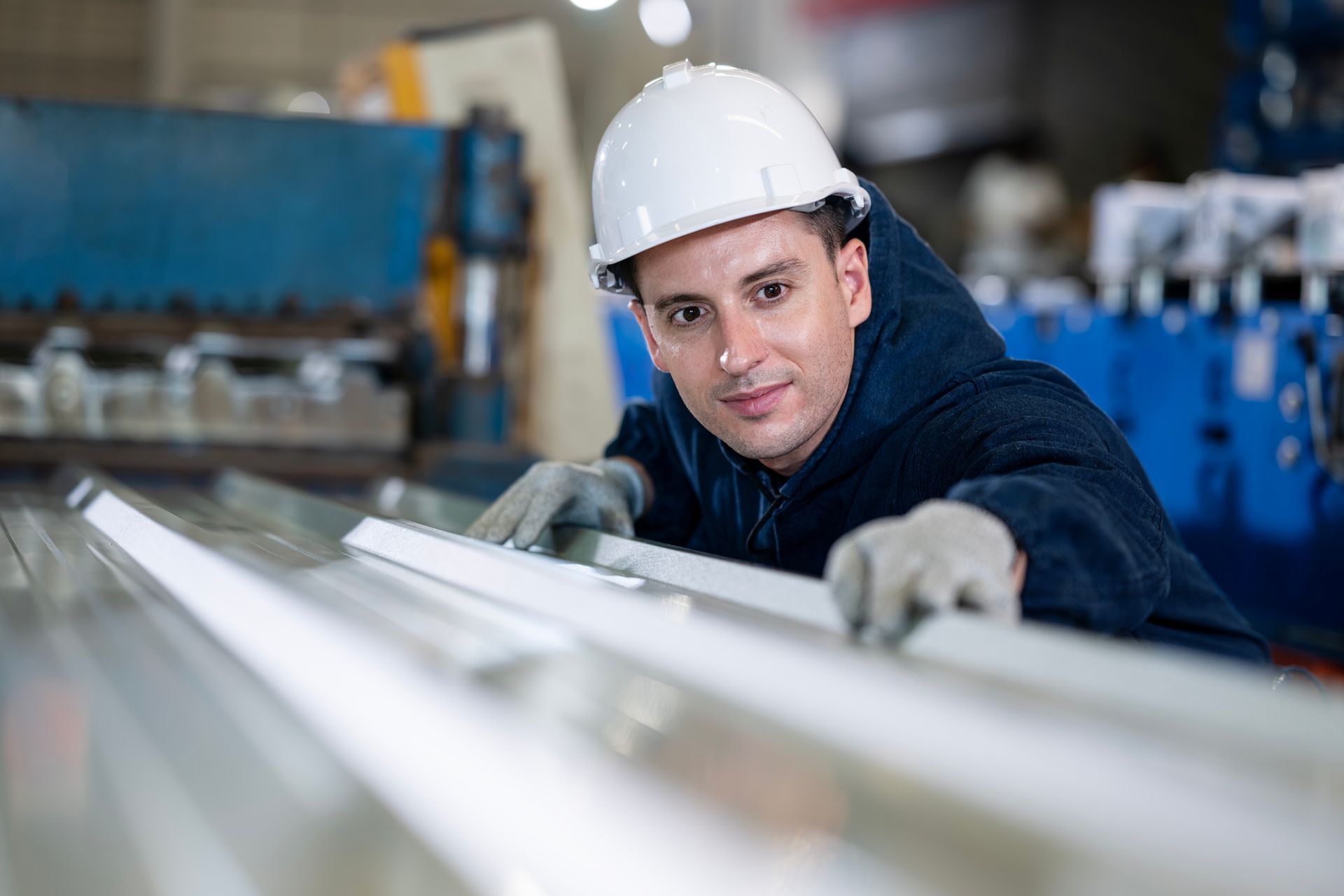 A man is examining the surface of a sheet of metal.