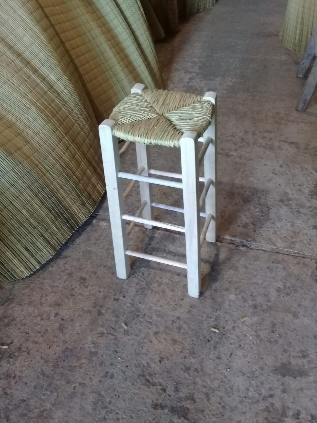 Un taburete alto de madera clara con asiento de paja tejida