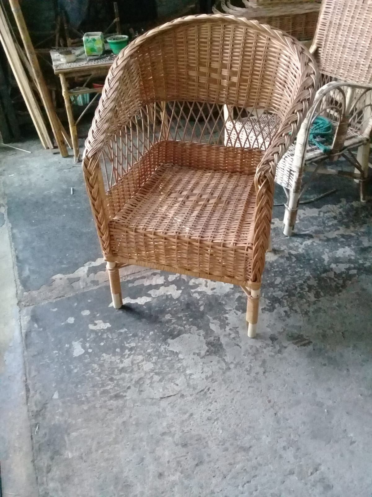 Una silla de mimbre de color marrón claro con respaldo redondeado y laterales