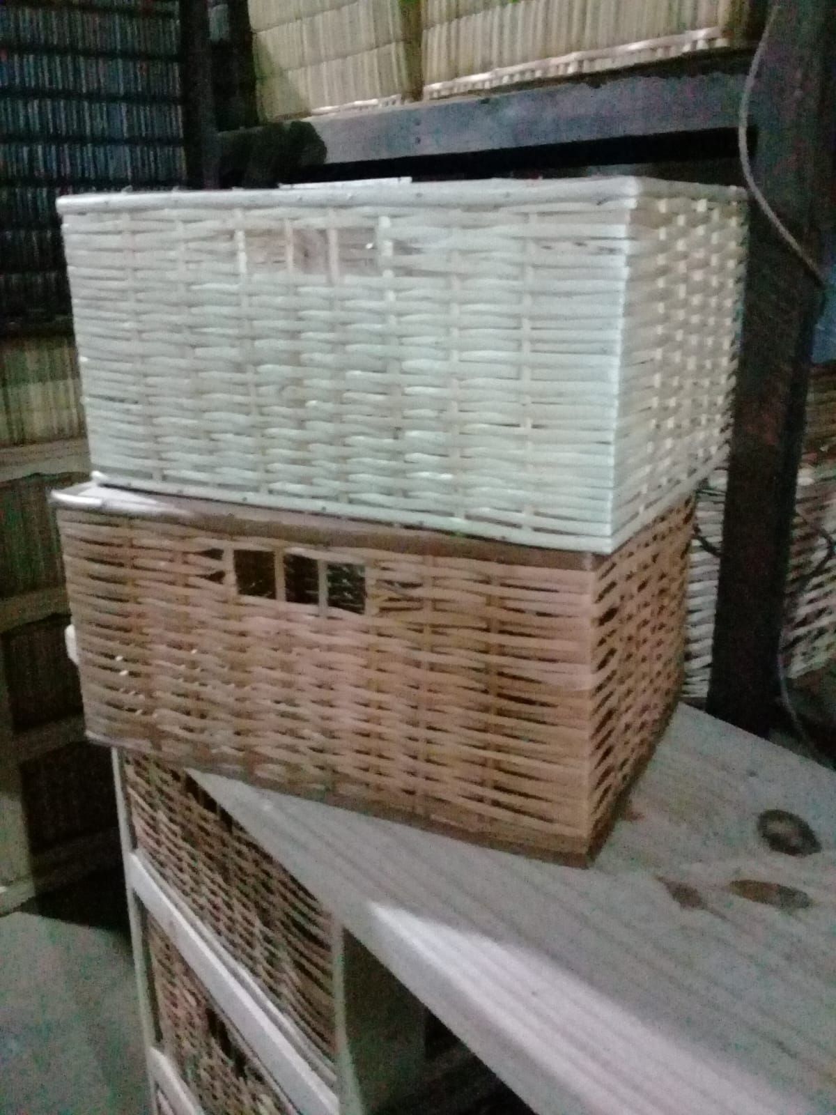 Dos cestas de almacenamiento rectangulares de mimbre apiladas en un estante, una blanca arriba y otra marrón abajo.