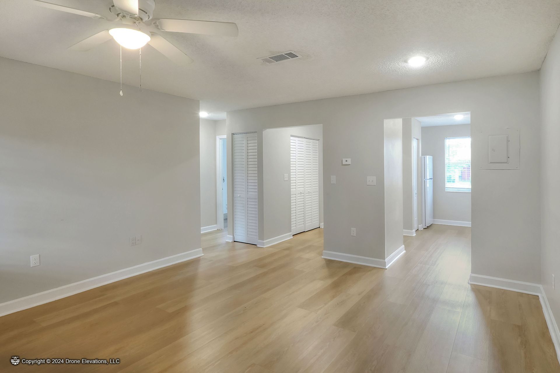 Empty living room with hardwood floors and light gray walls.
