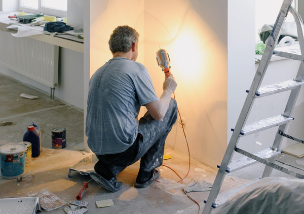 middle aged man drilling on drywall to the wall