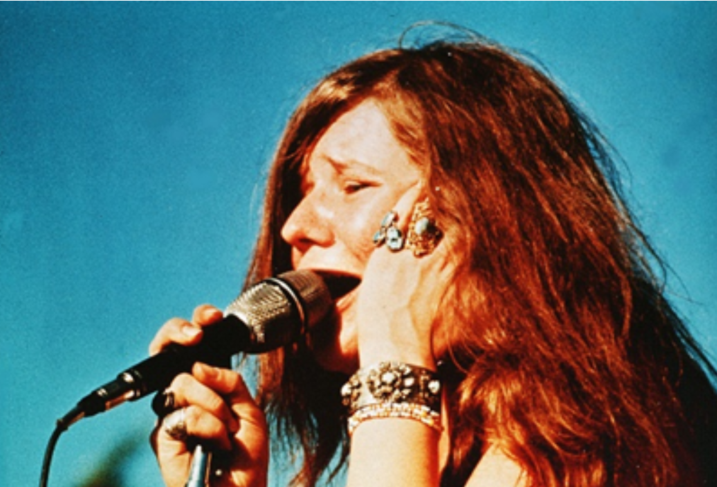 A woman singing into a microphone with a blue sky in the background