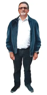 Stehender Mann, trägt eine blaue Jacke über einem weissen Hemd, dunkle Hosen und eine Brille.