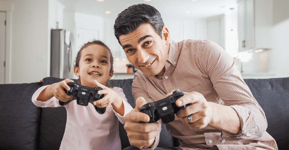 A father and daughter playing on a games console