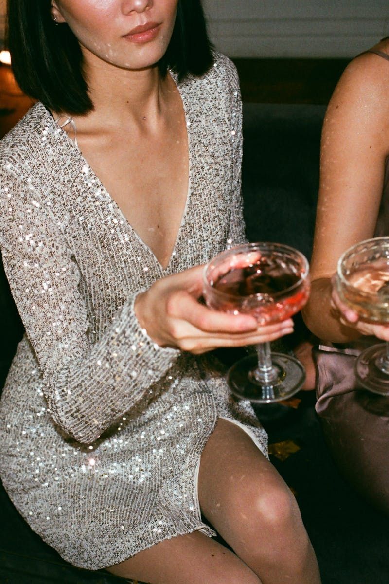 Une femme en robe à paillettes tient un cocktail.