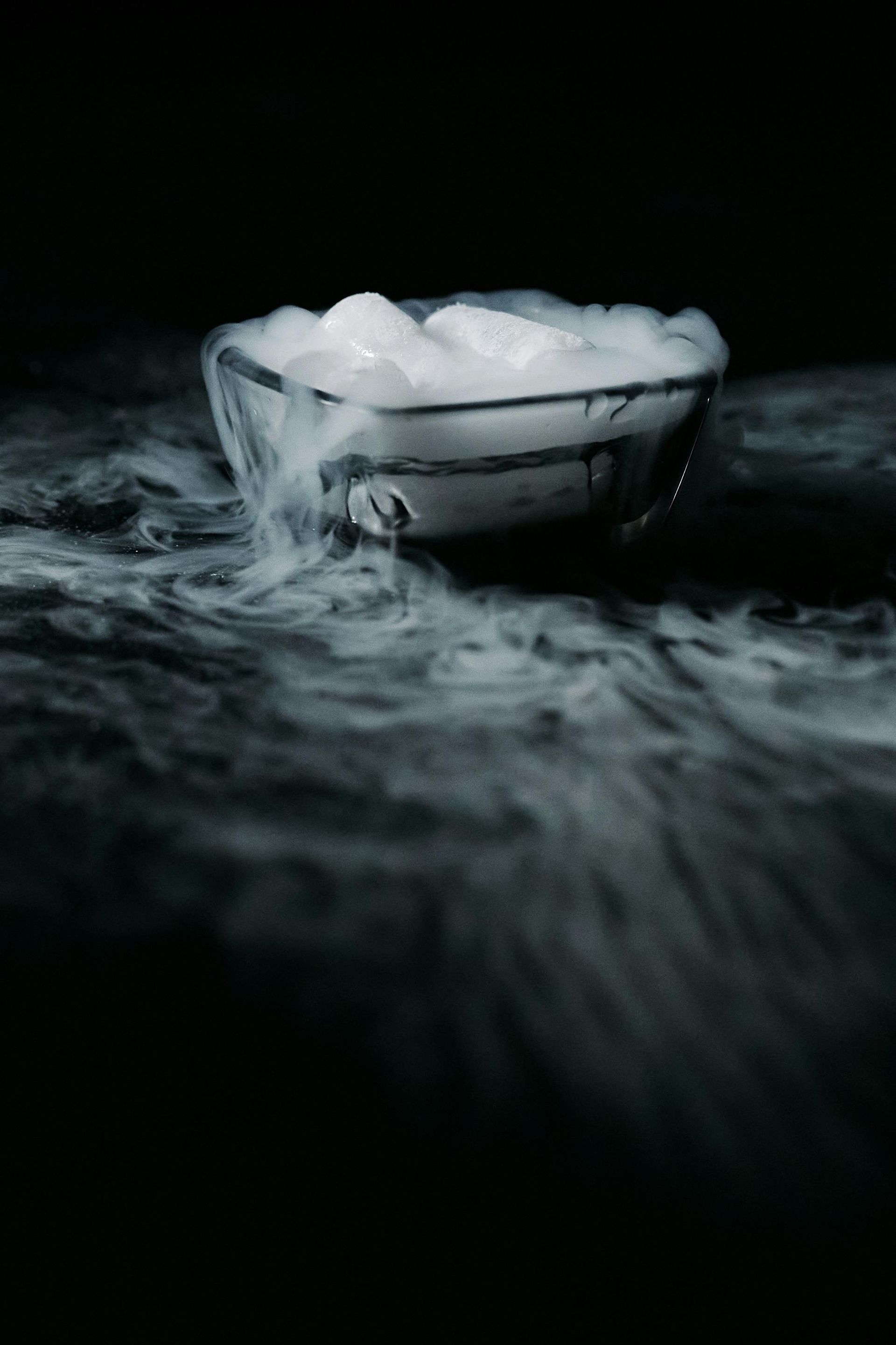 Bowl of white ice, emitting fog against a black backdrop.
