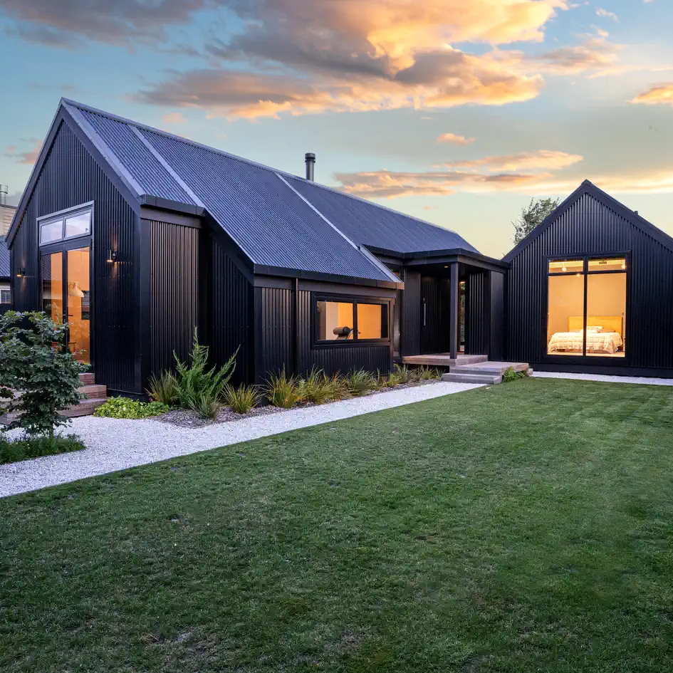 A black house with a large lawn in front of it.