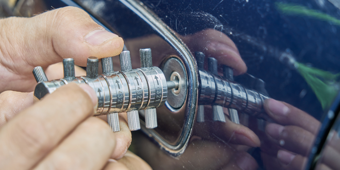 A person is using a key to open a car door.