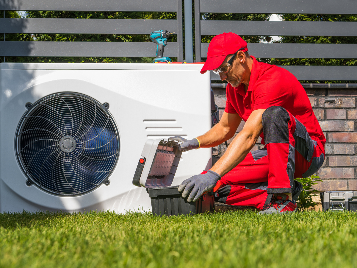 A man in a red shirt and black pants is replacing a heat pump in Westminster, Colorado.