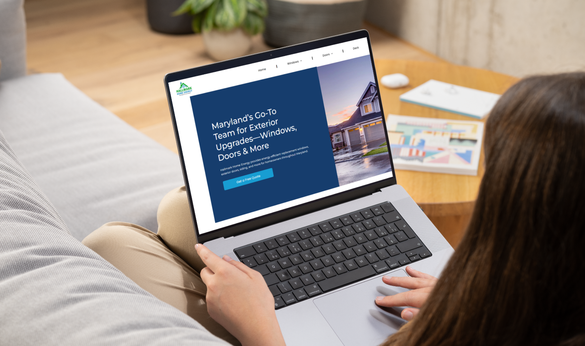 Woman using laptop, website open on screen, sitting on a couch.