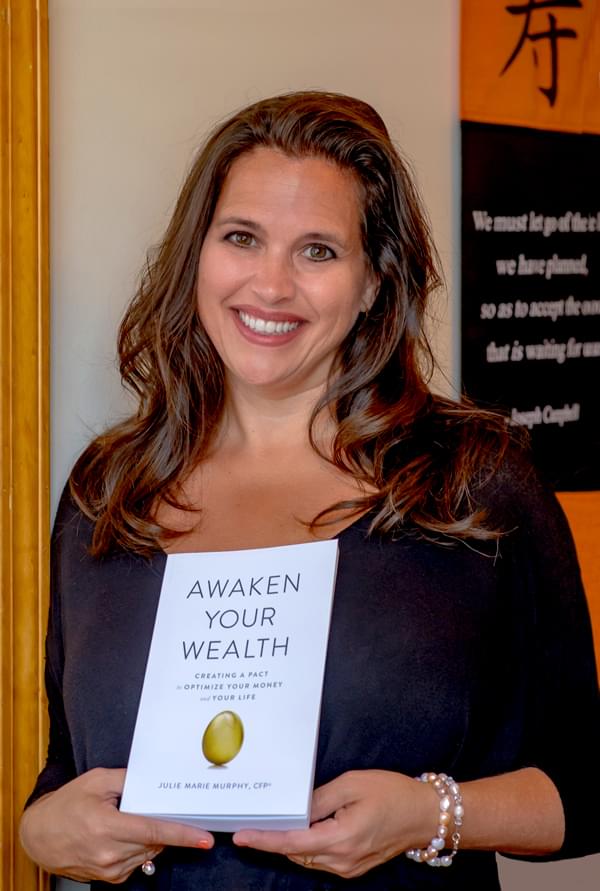 A woman is holding a book titled awaken your wealth