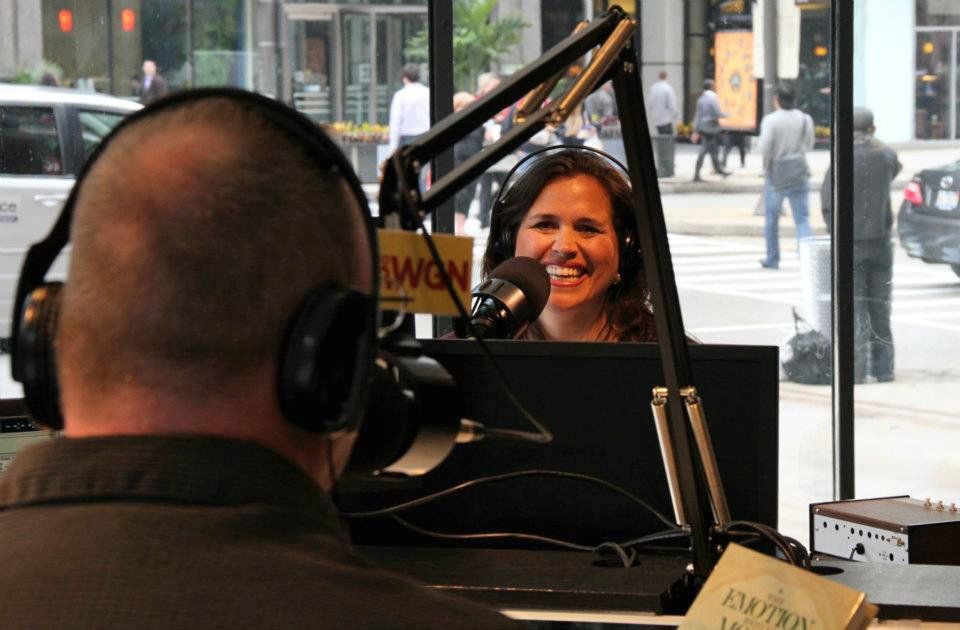 A woman is smiling in front of a microphone while wearing headphones